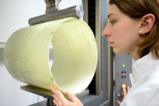 Frau mit weißem Kittel positioniert Materialprobe in Testapparatur