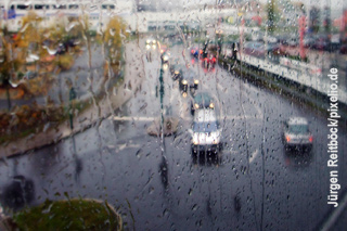 Blick durch nasses Fenster auf Straße und Platz