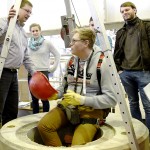 Student mit Sicherheitsausrüstung sitzt auf Schachtrand