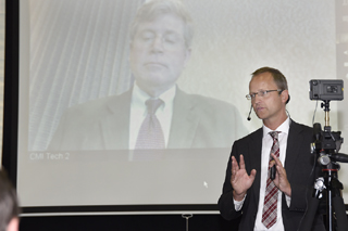 Mann mit Anzug vor Leinwand führt Webkonferenz