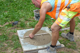 Bauarbeiter misst mit Zollstock das Ausbreitmaß einer Flüssigboden-Probe