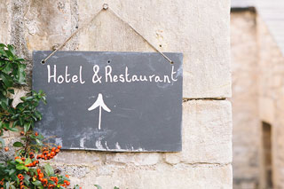 Schild mit Hinweis auf Hotel und Restaurant an Hauswand