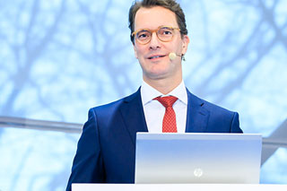 NRW-Verkehrsminister Hendrik Wüst mit Brille, blauem Anzug und roter Krawatte
