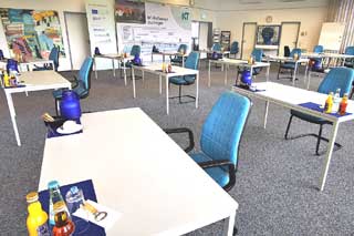 weiße Tische und blaue Stühle in einem Seminarraum