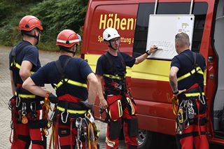 Feuerwehrleute bei der Einsatzbesprechung vor dem Einsatzfahrzeug